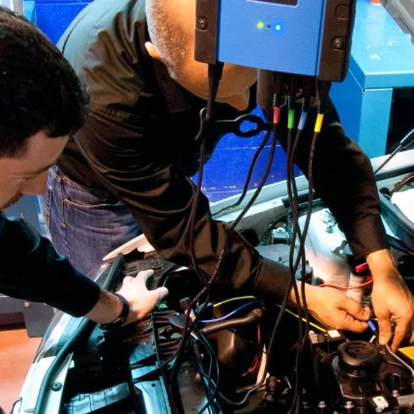 Dos mecánicos conectando un equipo de diagnosis al motor de un coche